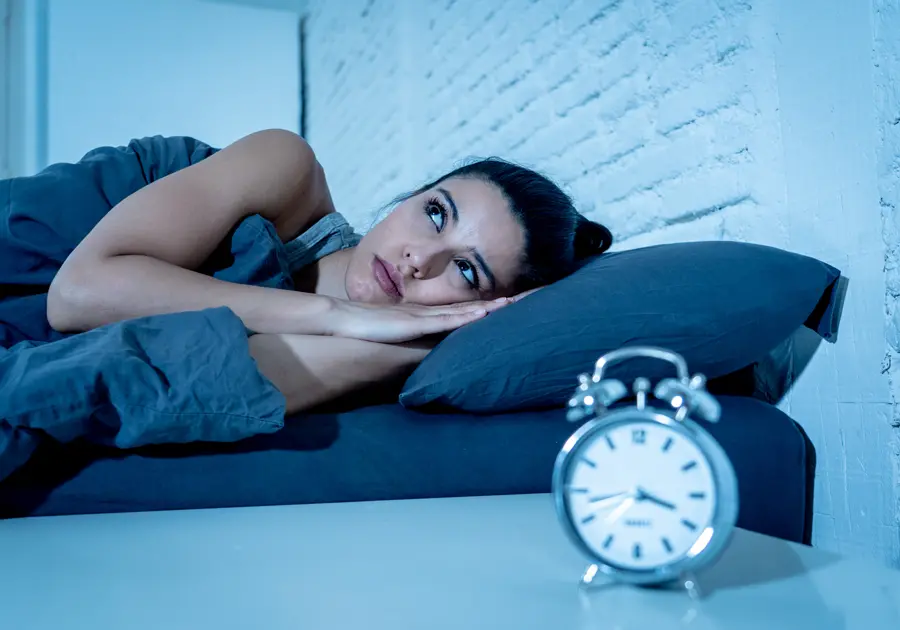Mujer con insomnio acostada en la cama mirando el reloj