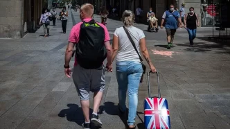 Turistas británicos paseando por España con maleta de la bandera del Reino Unido.