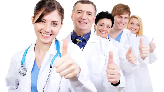Grupo de médicos sonriendo con pulgar arriba.