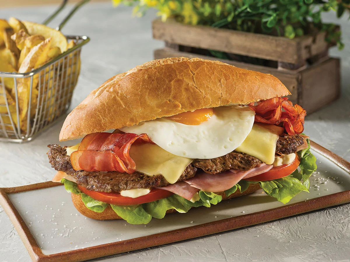 Variaciones del chivito uruguayo con huevo frito, panceta y carne