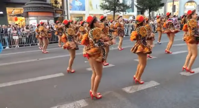 Mujeres con trajes bordados y zapatos rojos bailan en la Gran Vía durante la Cabalgata de la Hispanidad.