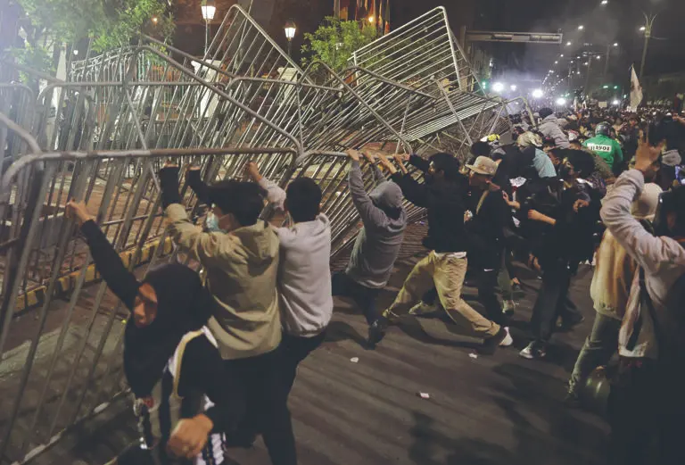 Protestas en Lima Perú con manifestantes intentando derribar vallas policiales.