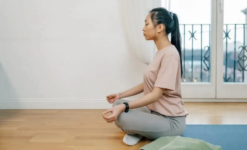 Mujer practicando meditación en casa para reducir el estrés.