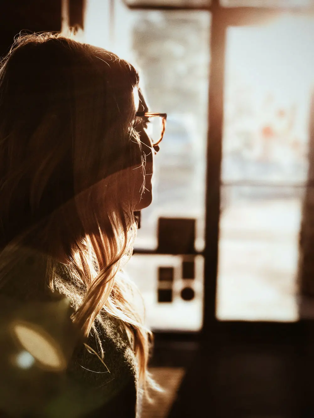 Mujer mirando hacia la luz al amanecer, en actitud reflexiva.