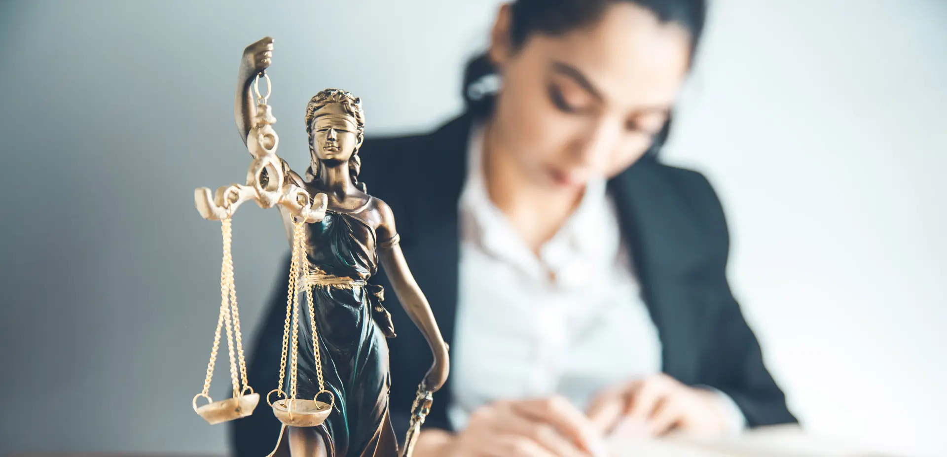 Estatua de la justicia con abogada de fondo estudiando.