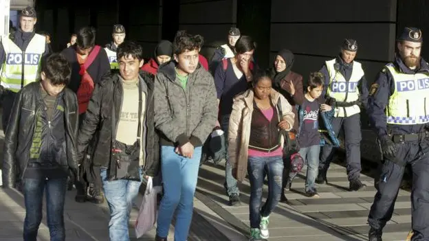 Grupo de migrantes acompañado por policías suecos durante un control en Estocolmo.