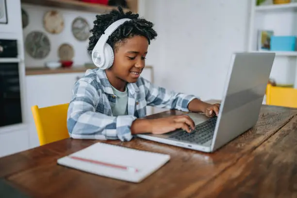 Niño estudia inglés en línea con auriculares y laptop