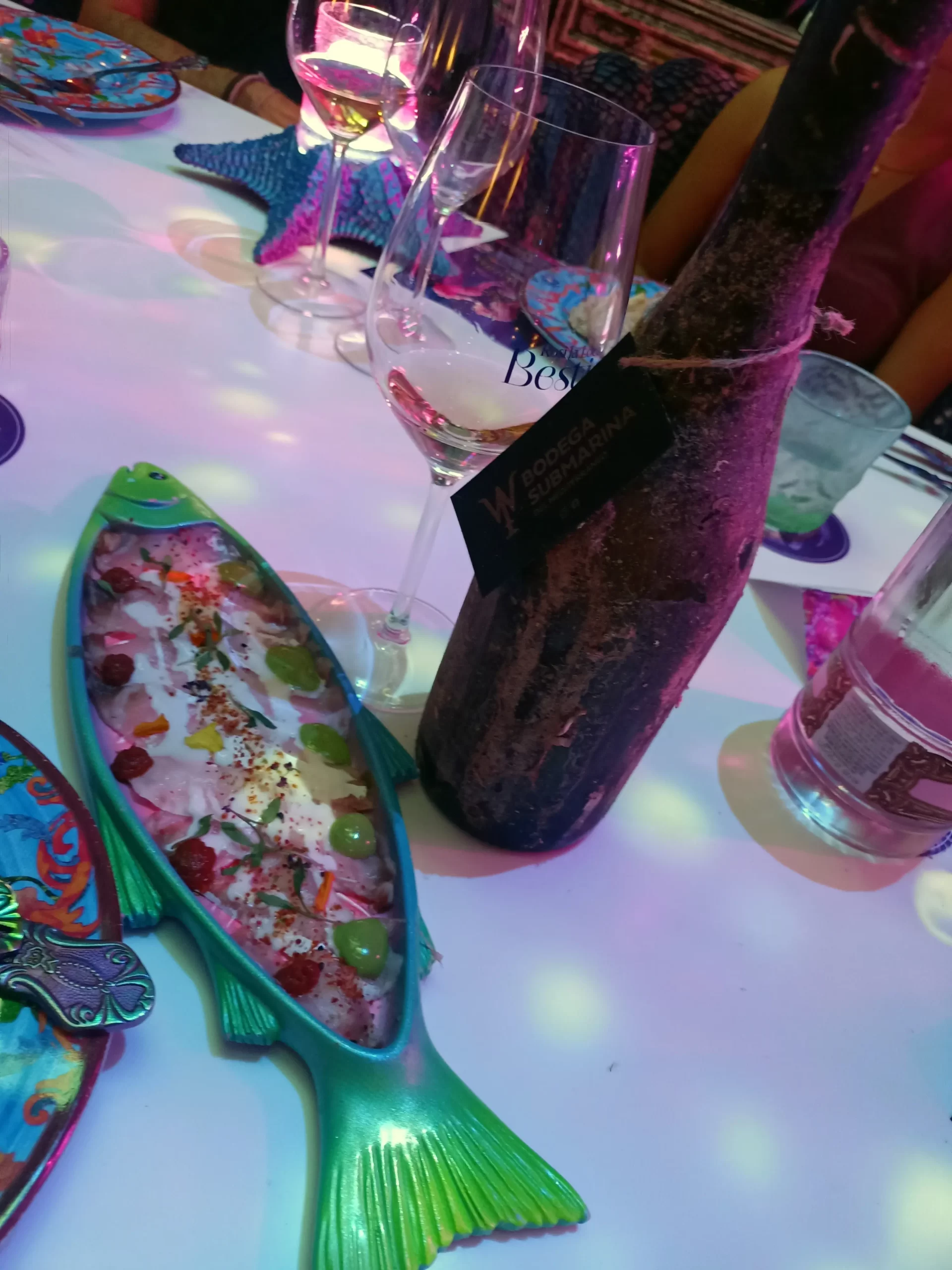 Vino submarino y plato de tiradito servidos en el restaurante Bestial de Madrid.