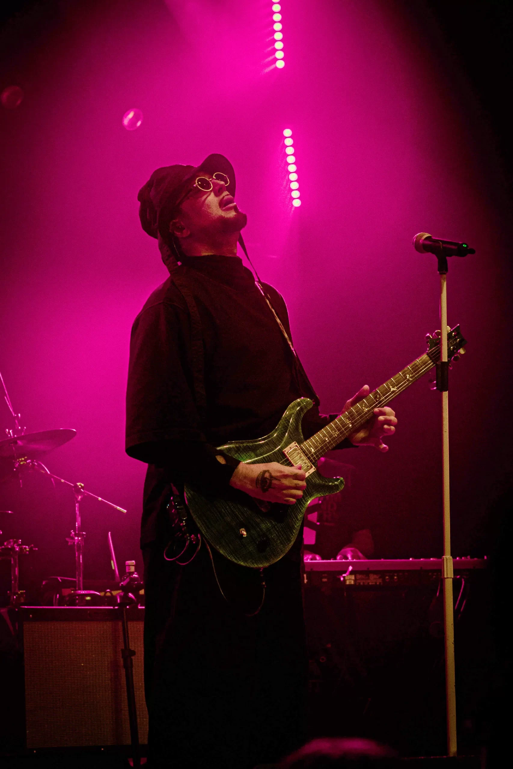 Artista en vivo durante JAZZMADRID 2025 tocando la guitarra en un escenario iluminado en magenta.