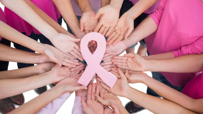Manos unidas alrededor de un lazo rosa símbolo del cáncer de mama.