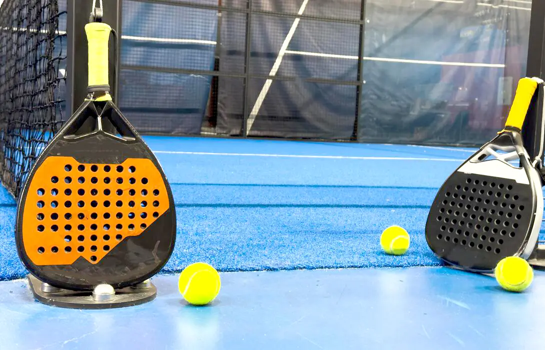 Auge del padel con raquetas y pelotas en cancha azul.