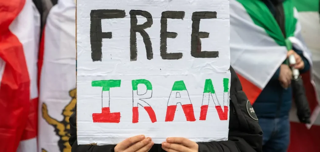 Protestas por la crisis en Irán con manifestantes sosteniendo un cartel de “Free Iran”.