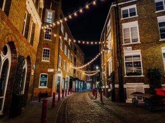 Invierno Reino Unido en una calle empedrada de Londres iluminada por luces nocturnas.