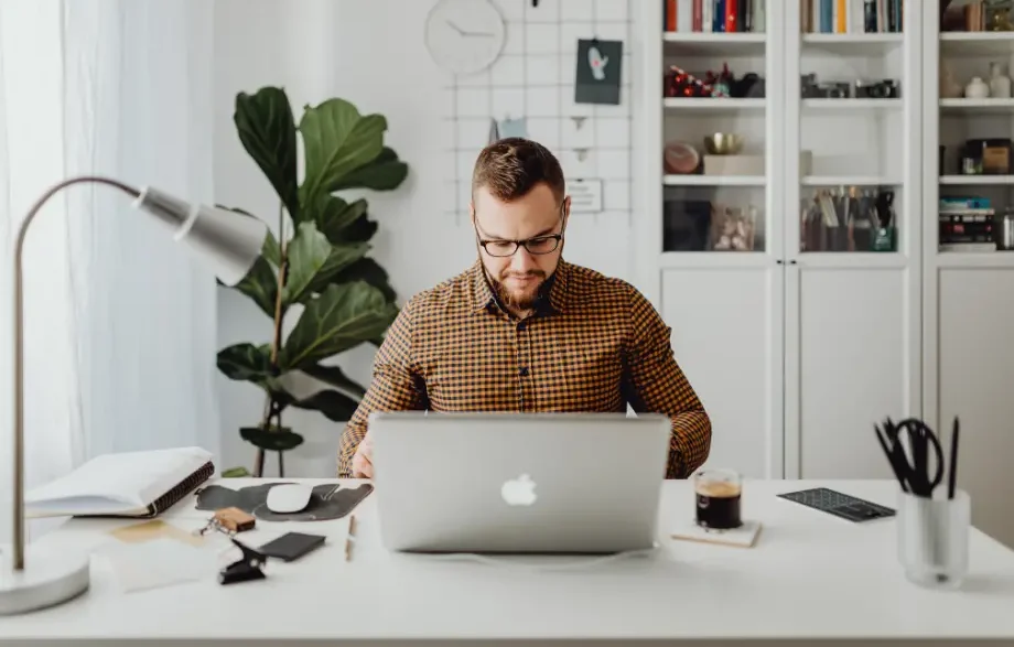 Teletrabajo hombre trabajando desde casa en oficina doméstica.