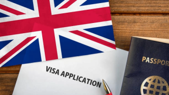 Reforma migratoria Reino Unido con formulario de visa y bandera británica sobre escritorio.