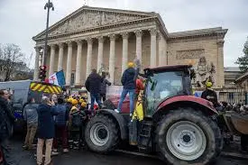 Protesta agricultores París con tractores frente a un edificio institucional en la capital francesa.