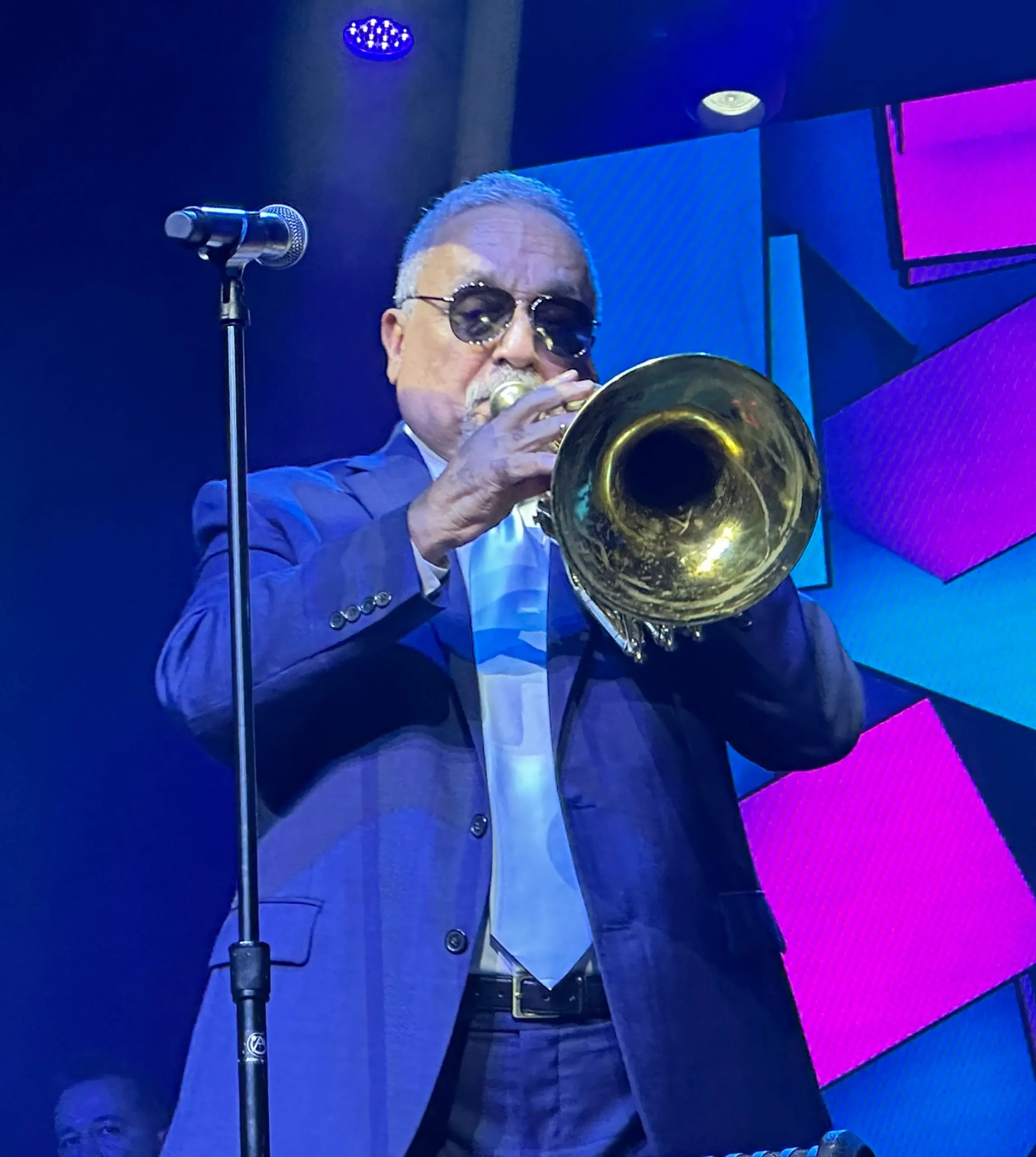 Willie Colón leyenda de la salsa tocando trombón en concierto.
