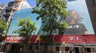 Sede del PSOE en la calle Ferraz de Madrid con pancarta “No a la corrupción” y gran cartel publicitario del partido durante obras en la fachada