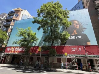 Sede del PSOE en la calle Ferraz de Madrid con pancarta “No a la corrupción” y gran cartel publicitario del partido durante obras en la fachada