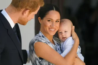 El príncipe Harry y Meghan Markle caminando de la mano con uno de sus hijos durante un acto público.