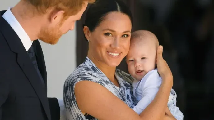 El príncipe Harry y Meghan Markle caminando de la mano con uno de sus hijos durante un acto público.