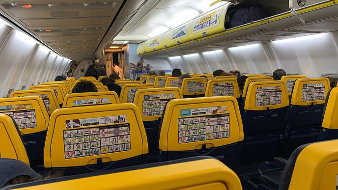 Interior de una cabina de avión de Ryanair con asientos amarillos y azules.