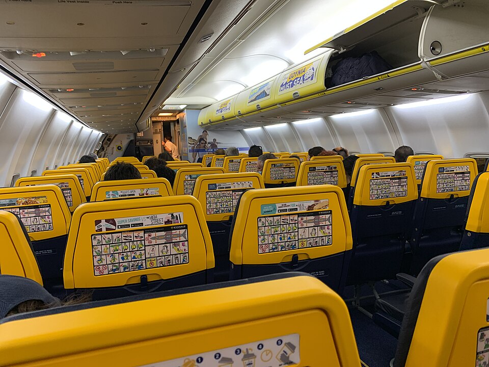 Interior de una cabina de avión de Ryanair con asientos amarillos y azules.