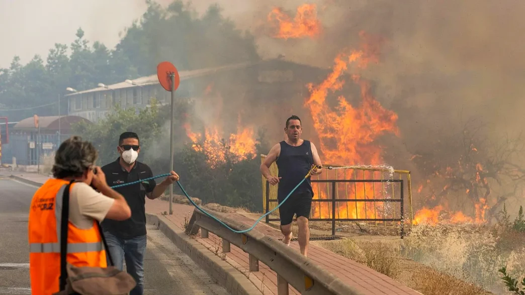 Vecinos intentan sofocar con una manguera el incendio forestal del parque regional de El Valle-Carrascoy en Murcia, donde las llamas han arrasado 177 hectáreas en junio de 2026