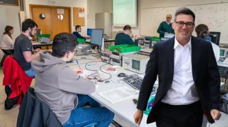 Andy Burnham sonriente en un aula técnica junto a jóvenes estudiantes.