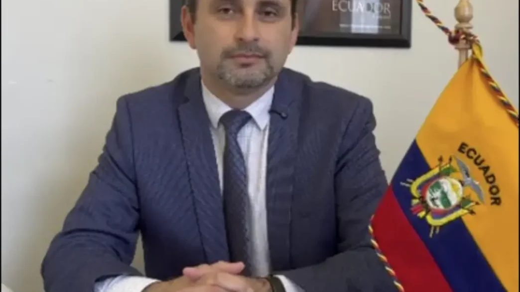 El Cónsul Christian Valencia sentado en su despacho de la Sección Consular de la Embajada del Ecuador en París junto a la bandera del país.