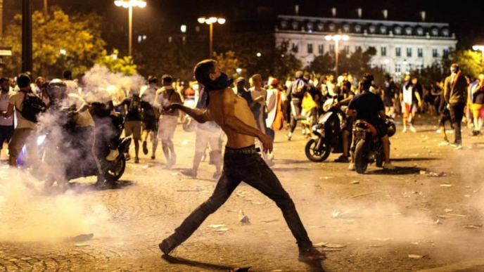 Manifestante lanzando objetos durante los disturbios en las calles de París tras el partido Francia contra Marruecos.