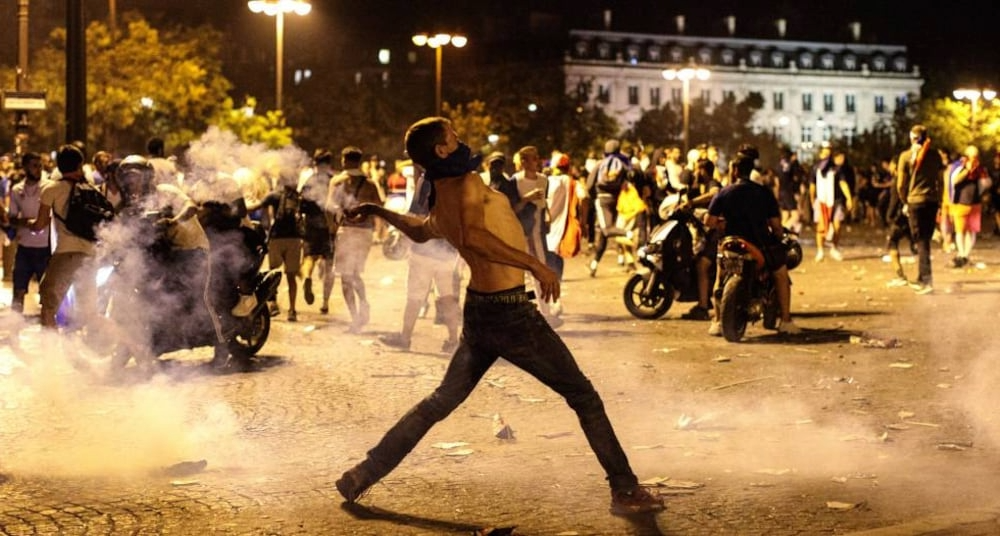 Manifestante lanzando objetos durante los disturbios en las calles de París tras el partido Francia contra Marruecos.