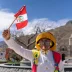 Persona con indumentaria tradicional y máscara sosteniendo una pequeña bandera de Perú durante las celebraciones.