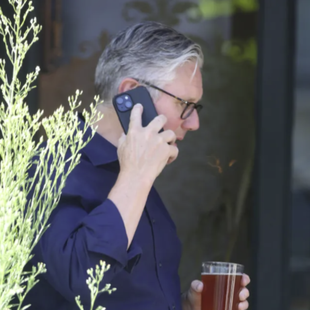 Sir Keir Starmer sosteniendo una pinta de cerveza y hablando por teléfono tras su dimisión.