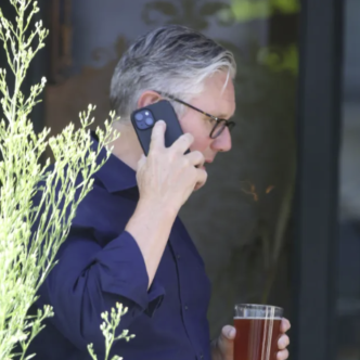 Sir Keir Starmer sosteniendo una pinta de cerveza y hablando por teléfono tras su dimisión.
