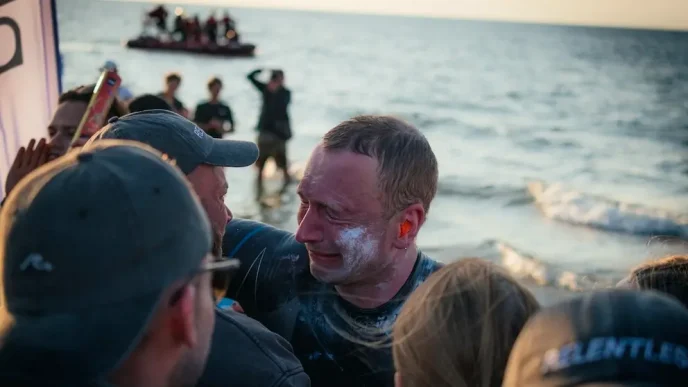 El nadador Bartłomiej Kubkowski emocionado en la playa tras completar su hazaña contra el cáncer.