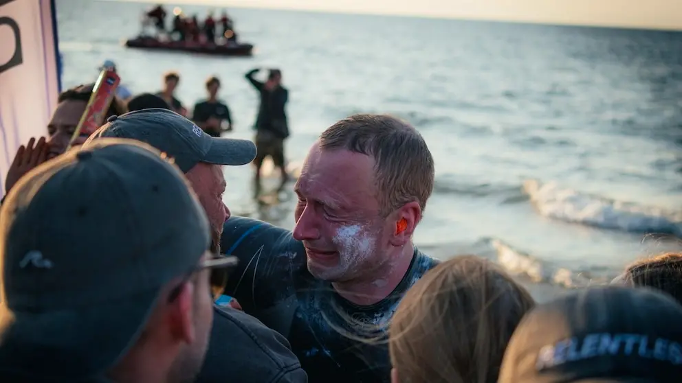 El nadador Bartłomiej Kubkowski emocionado en la playa tras completar su hazaña contra el cáncer.