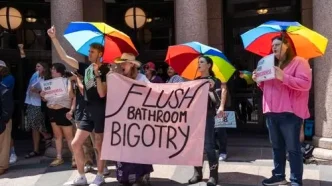 Manifestantes con paraguas de colores y pancartas protestando en apoyo a los derechos de las personas trans en Londres.