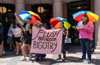 Manifestantes con paraguas de colores y pancartas protestando en apoyo a los derechos de las personas trans en Londres.
