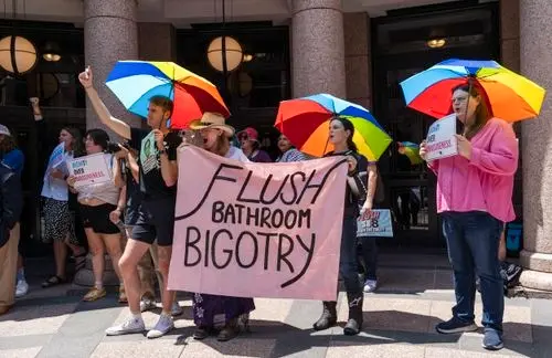 Manifestantes con paraguas de colores y pancartas protestando en apoyo a los derechos de las personas trans en Londres.