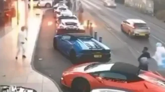 Varios superdeportivos aparcados en la calle mientras se aprecia un destello de fuego cerca