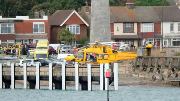 Helicóptero médico amarillo de emergencias estacionado junto a la costa y viviendas en Shoreham Beach