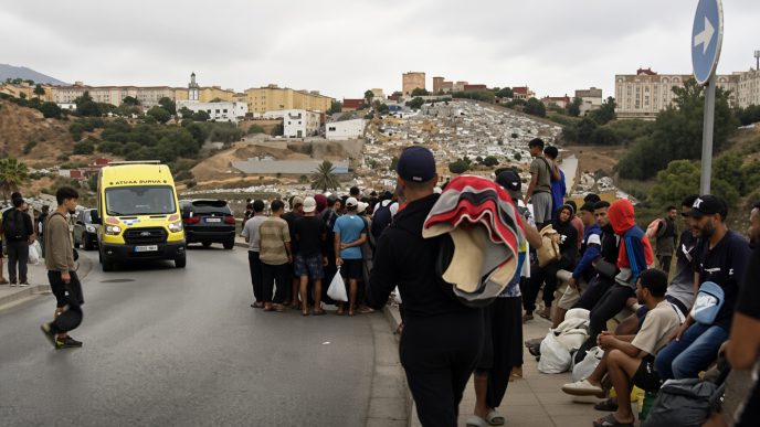Grupo de migrantes y una ambulancia en una carretera tras la llegada masiva a Ceuta