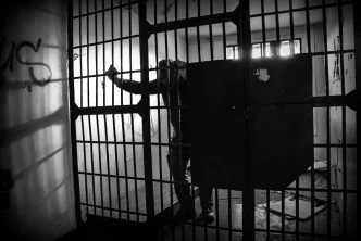 Recluso tras los barrotes de una celda de prisión