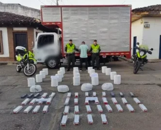 Autoridades policiales junto a un camión intervenido y material explosivo incautado en un operativo en Colombia.