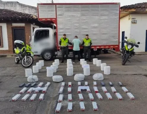 Autoridades policiales junto a un camión intervenido y material explosivo incautado en un operativo en Colombia.
