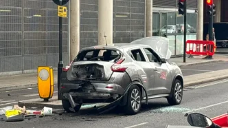 Coche plateado dañado con cristales rotos y el capó abierto tras la explosión controlada