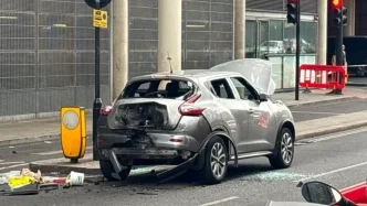 Coche plateado dañado con cristales rotos y el capó abierto tras la explosión controlada