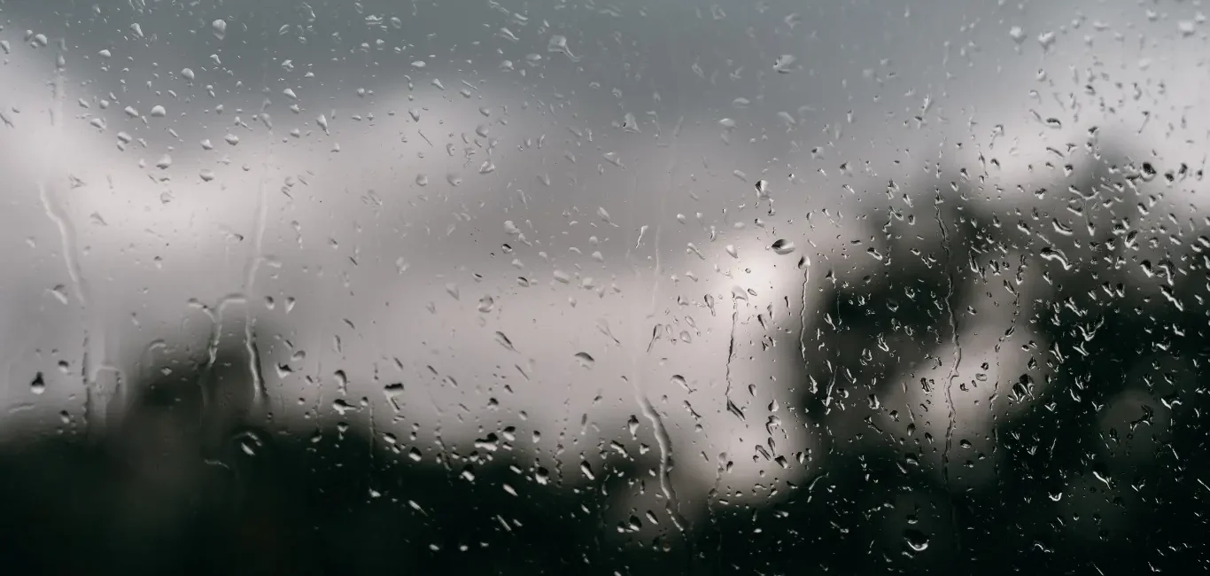 Gotas de lluvia cayendo sobre una ventana con un fondo nublado en Londres