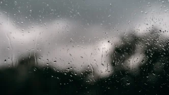 Gotas de lluvia cayendo sobre una ventana con un fondo nublado en Londres